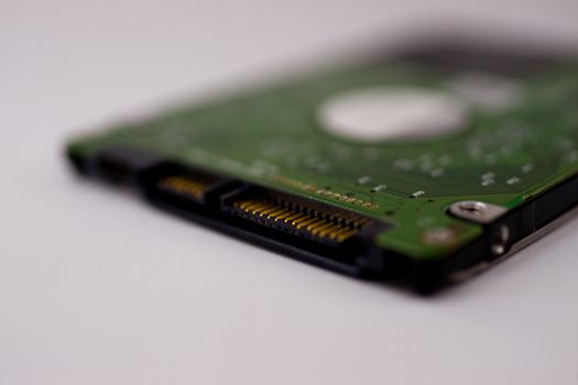 2.5mm laptop HDD on white blurred background. A lot of space on photo is defocused or have soft focus.