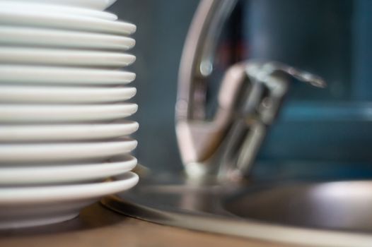 A lot of clean dish on table near sink in cafe. Close-up view