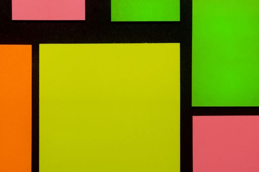 Green, yellow, orange and rose hue colorful office stickers on black paper. Office noteparer as reminder. Isolated on black paper.