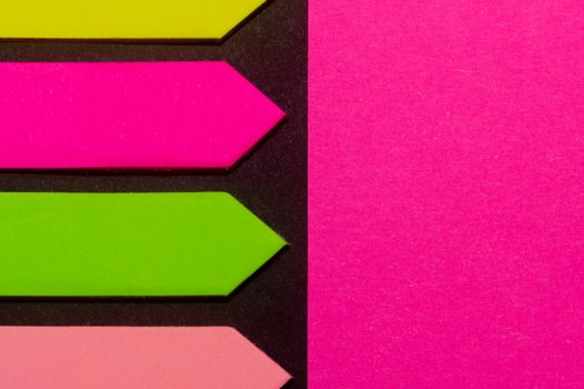 Green, yellow, purple and rose hue colorful office stickers on black paper. Office noteparer as reminder. Isolated on black paper.