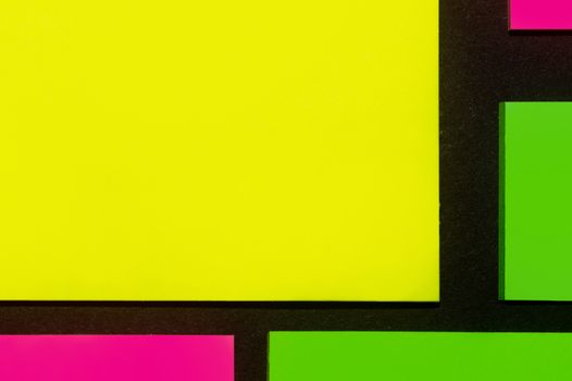 Green, yellow and purple hue colorful office stickers on black paper. Office noteparer as reminder. Isolated on black paper.