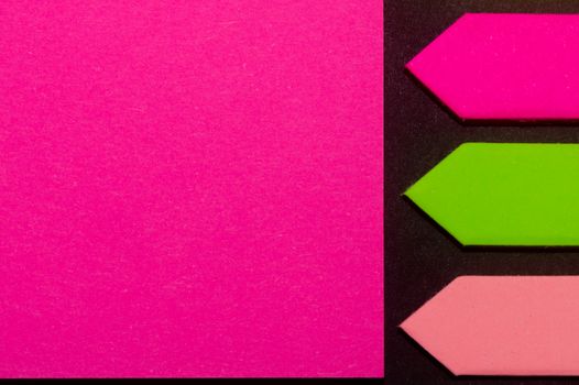 Green, purple and rose hue colorful office stickers on black paper. Office noteparer as reminder. Isolated on black paper.