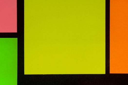 Green, yellow, orange and rose hue colorful office stickers on black paper. Office noteparer as reminder. Isolated on black paper.