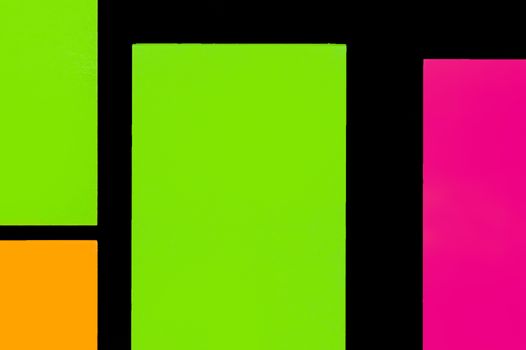 Green, orange and purple hue colorful office stickers on black paper. Office noteparer as reminder. Isolated on black paper.