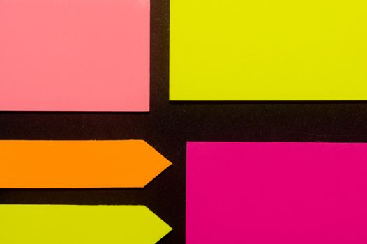 Purple, yellow, orange and rose hue colorful office stickers on black paper. Office noteparer as reminder. Isolated on black paper.