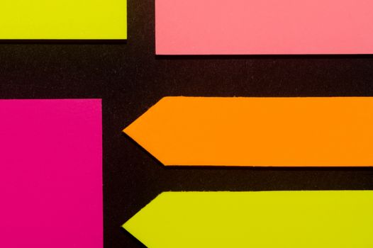 Purple, yellow, orange and rose hue colorful office stickers on black paper. Office noteparer as reminder. Isolated on black paper.