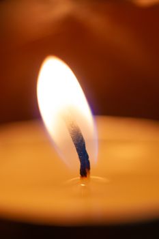 Underexposed low light photo of candle in aromatic lamp. Close-up view