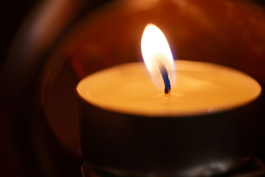 Underexposed low light photo of candle in aromatic lamp. Close-up view