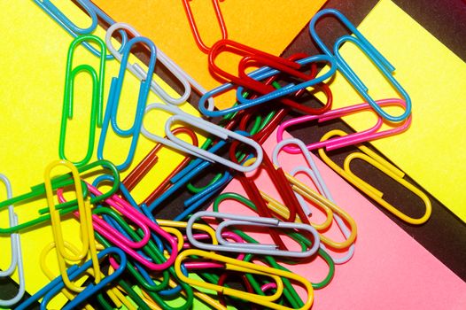 Paperclips on colorful different colour office stickers on black paper.