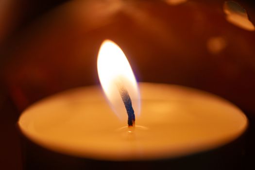 Underexposed low light photo of candle in aromatic lamp. Close-up view