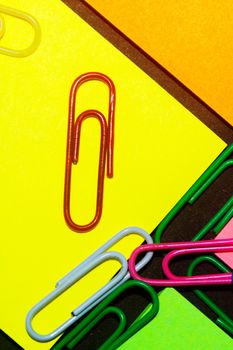 Paperclips on colorful different colour office stickers on black paper.