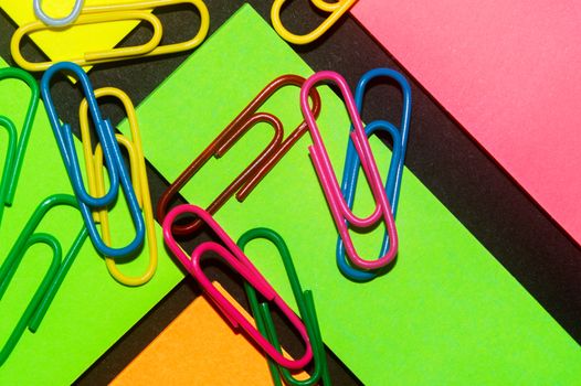 Paperclips on colorful different colour office stickers on black paper.