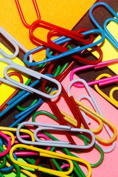 Paperclips on colorful different colour office stickers on black paper.