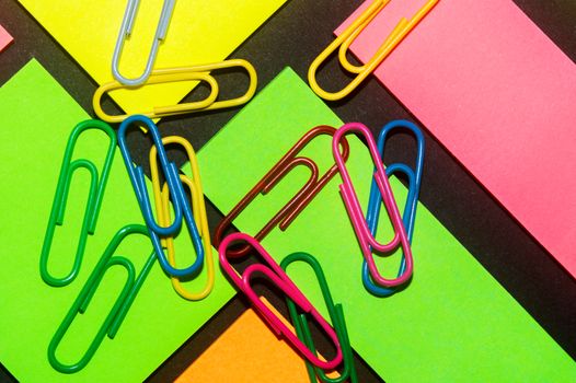 Paperclips on colorful different colour office stickers on black paper.