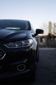 Modern car headlamps shot. Nice car eyes. Half of car on photo, blurred background. Cose up view. Aggressive car eyes.