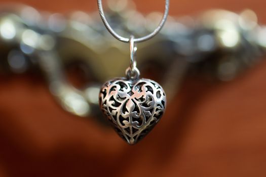 Close up photo of female neck silver pendand on blurred background. A handwork sterling silver pendant look as heart. Macrophoto with blurred background.