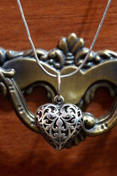 Close up photo of female neck silver pendand on blurred background. A handwork sterling silver pendant look as heart. Macrophoto with blurred background.