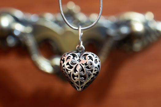 Close up photo of female neck silver pendand on blurred background. A handwork sterling silver pendant look as heart. Macrophoto with blurred background.