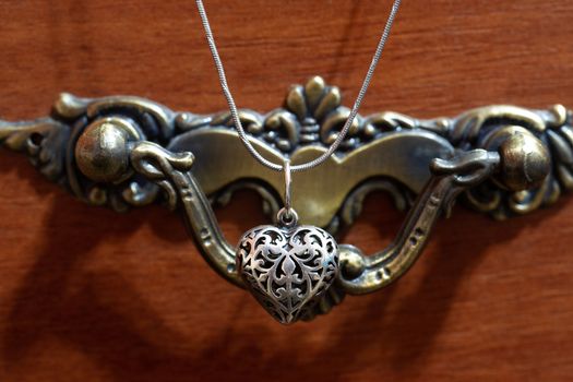 Close up photo of female neck silver pendand on blurred background. A handwork sterling silver pendant look as heart. Macrophoto with blurred background.