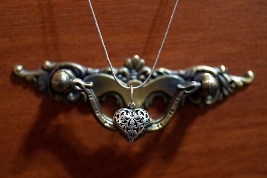 Close up photo of female neck silver pendand on blurred background. A handwork sterling silver pendant look as heart. Macrophoto with blurred background.