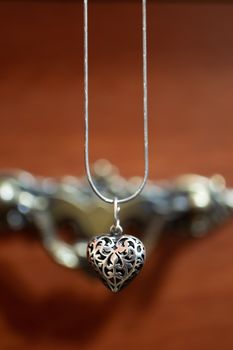 Close up photo of female neck silver pendand on blurred background. A handwork sterling silver pendant look as heart. Macrophoto with blurred background.