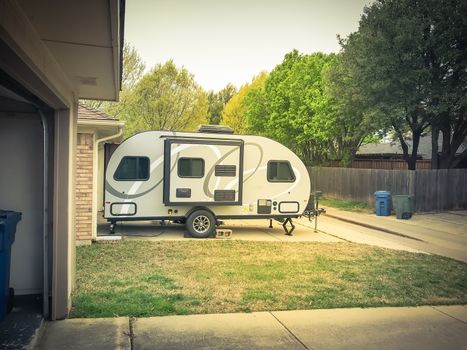 Side view of RV trailer parked at house garage backyard