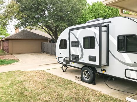 Side view of RV trailer parked at house garage backyard