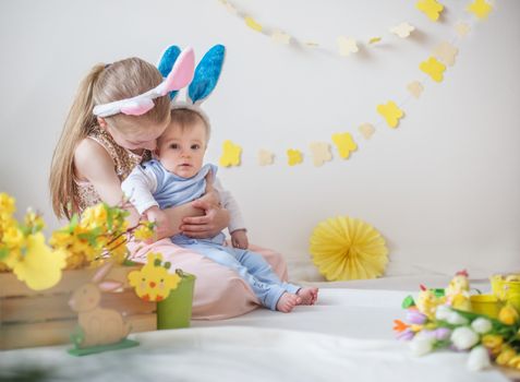 Loving cute girl and her little brother wearing bunny ears in Easter decor