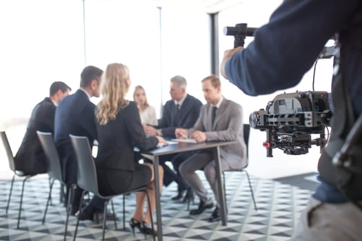 Videographer filming group of people at business meeting