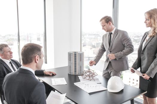 Construction presentation on office , two business people showing model of their project