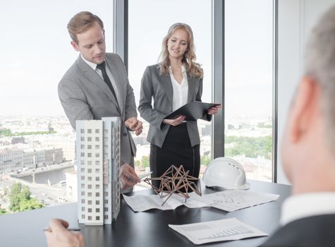 Construction presentation on office , two business people showing model of their project