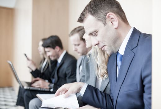 Applicants preparing for employment interview sitting on chairs in queue row line waiting, job hunting concept