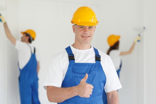 Workman gives thumbs up in front of two painters