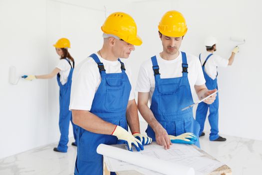 Workers discuss renovation project , two wall painters on background
