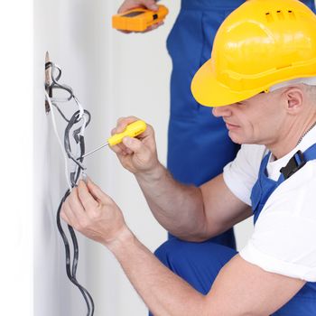 Two builders working with electricity indoors in new house