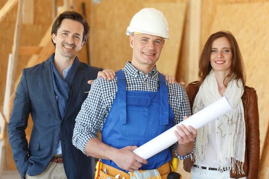 Foreman shows new house to a young couple holding blueprint