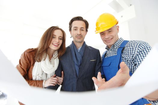 Foreman shows new house to a young couple holding blueprint