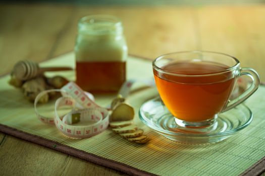 Ginger juice in a clear cup and honey jar placed beside with measuring tape.
Concept of healthy.