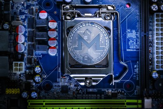 Top view of Monero cryptocurrency physical coin on computer mother board processor.Bitcoin mining farm, working computer equipment concept.