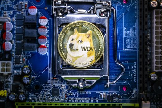 Top view of Dogecoin cryptocurrency physical coin on computer mother board processor.Bitcoin mining farm, working computer equipment concept.