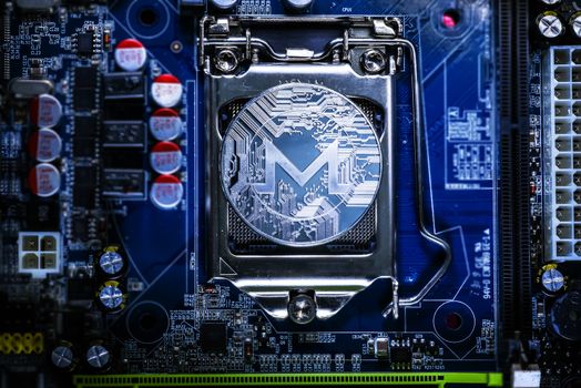 Top view of Monero cryptocurrency physical coin on computer mother board processor.Bitcoin mining farm, working computer equipment concept.
