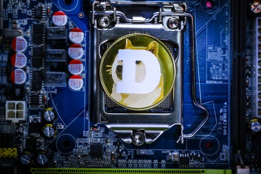 Top view of Dogecoin cryptocurrency physical coin on computer mother board processor.Bitcoin mining farm, working computer equipment concept.