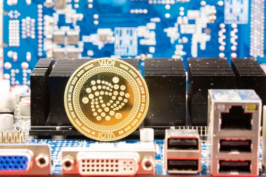 Front view of Iota cryptocurrency over computer video card.Bitcoin mining farm, working computer equipment concept.