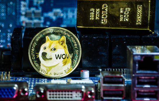 Front view of Dogecoin cryptocurrency and golden brick or block over computer video card.Bitcoin mining farm, working computer equipment concept.