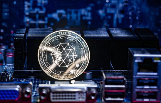 Front view of Qtum cryptocurrency over computer video card.Bitcoin mining farm concept.