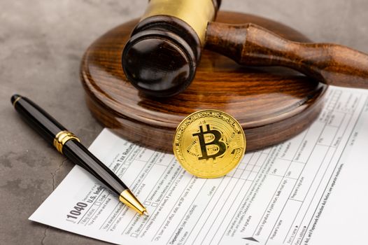 Front view of Bitcoin cryptocurrency in ront of gavel with pen.Tax paying concept. 