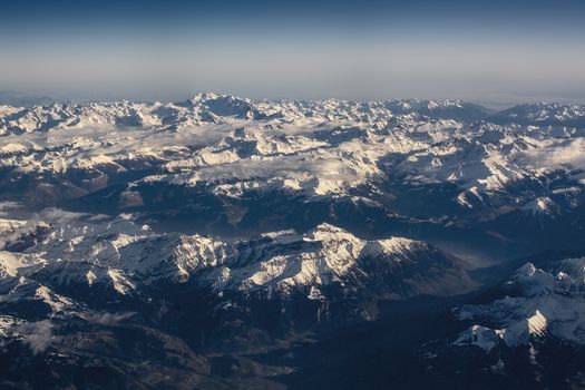 Swiss Alpes with snowy mountain tops aerial view towards the east during afternoon flight in December