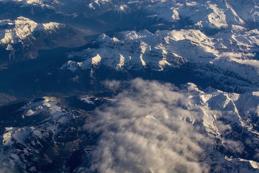 Swiss Alpes with snowy mountain tops aerial view towards the east during afternoon flight in December