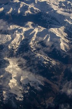 Swiss Alpes with snowy mountain tops aerial view towards the east during afternoon flight in December