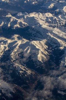 Swiss Alpes with snowy mountain tops aerial view towards the east during afternoon flight in December